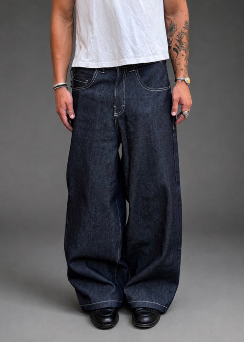 Divine 144 baggy raw indigo denim jeans with a wide straight-leg fit and contrast stitching on a model